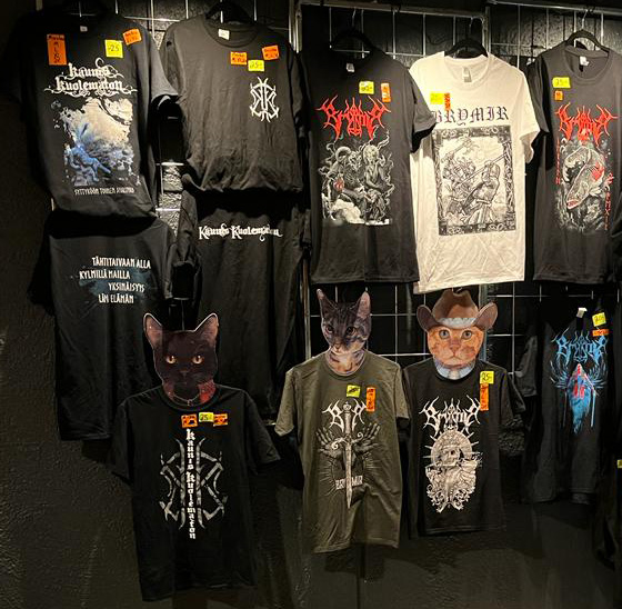 Brymir and Kaunis Kuolematon t-shirts for sale, hanging on display against a black wall..
