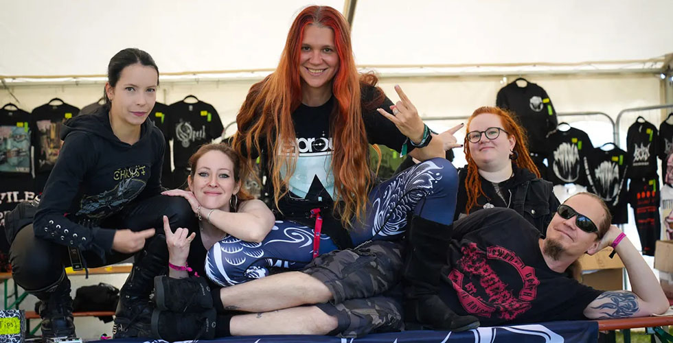 Janetta, Fanny, Chrissy, Katri and Aaro huddled together on the merchandise table at the North of Hell festival.